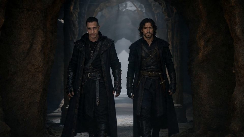 Two dark-clad hunters walking through a misty cave temple